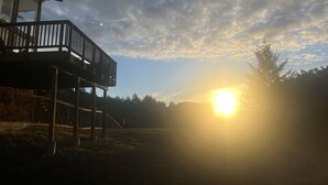 A wooden deck with a railing, a brick wall, and a clear sky with the sun setting or rising. - Sweeping Views, Private Deck,  Outdoor Spa #2 (Nicasio)