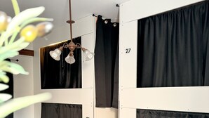 Huoneessa on harmaa matto, kattotuuletin ja mustat verhot ikkunoissa.