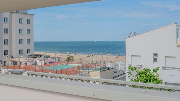 Vue d’une piscine sur le toit, offrant une vue dégagée sur la plage et l’océan.