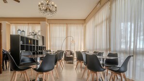 Un espace de salle à manger moderne avec des chaises noires, une table ronde et un lustre.