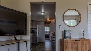A modern kitchen with a built-in refrigerator, a wooden cabinet, and a large flat-screen TV on a stand. - Modern River Retreat Near Airport, Hospitals, Corporations (Wyandotte)