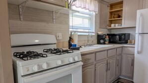 A compact kitchen with a white stove, sink, and microwave. - Modern River Retreat Near Airport, Hospitals, Corporations (Wyandotte)