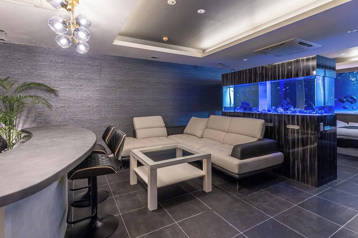 A modern living room with a bar area, a large aquarium, and a seating arrangement.
