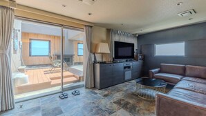 A modern living room with a leather sofa, a flat-screen TV, a coffee table, and a sliding glass door leading to a balcony. - HOTEL felice Osaka Itami airport (Toyonaka)