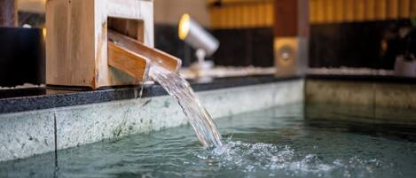 Una fuente de madera con agua que fluye hacia una piscina.