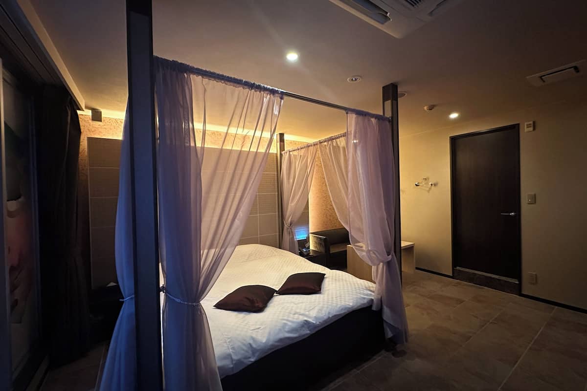 A modern bedroom with a four-poster bed, a bedside table, and a nightstand.