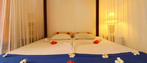 A double bed with white and red pillows, a blue bedspread, and white and red flowers.