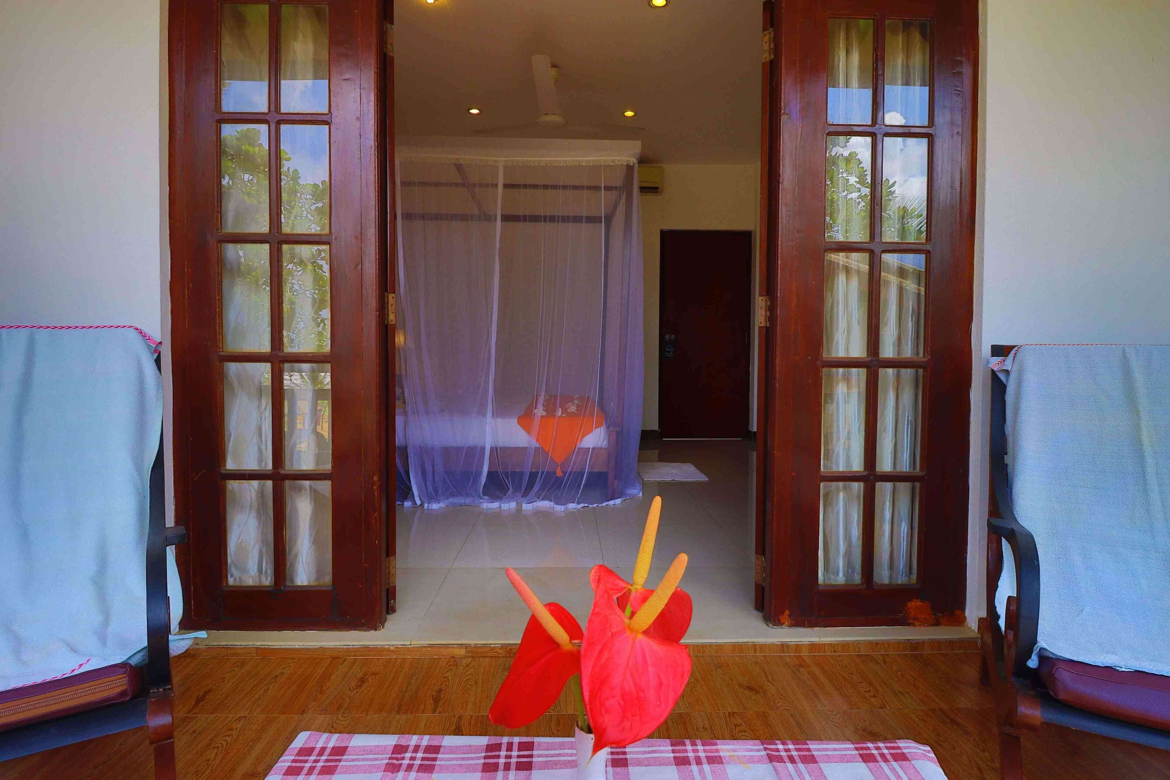 A room with a bed, a chair, a table, and a window with a view of the outdoors.