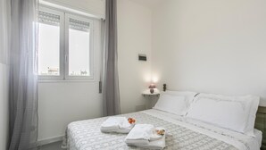 Une chambre d’hôtel avec un lit, une table de chevet, une fenêtre avec des rideaux et une vue sur l’extérieur.