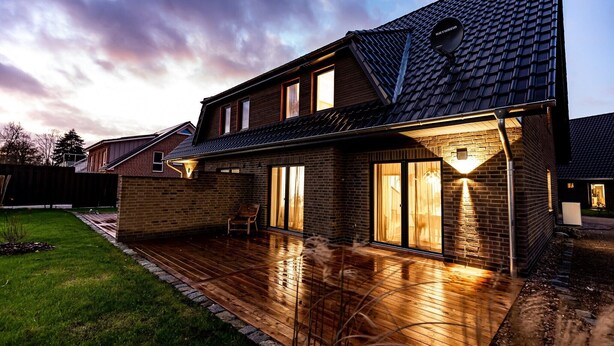 A two-story house with a sloped roof, a covered patio, and a brick exterior.