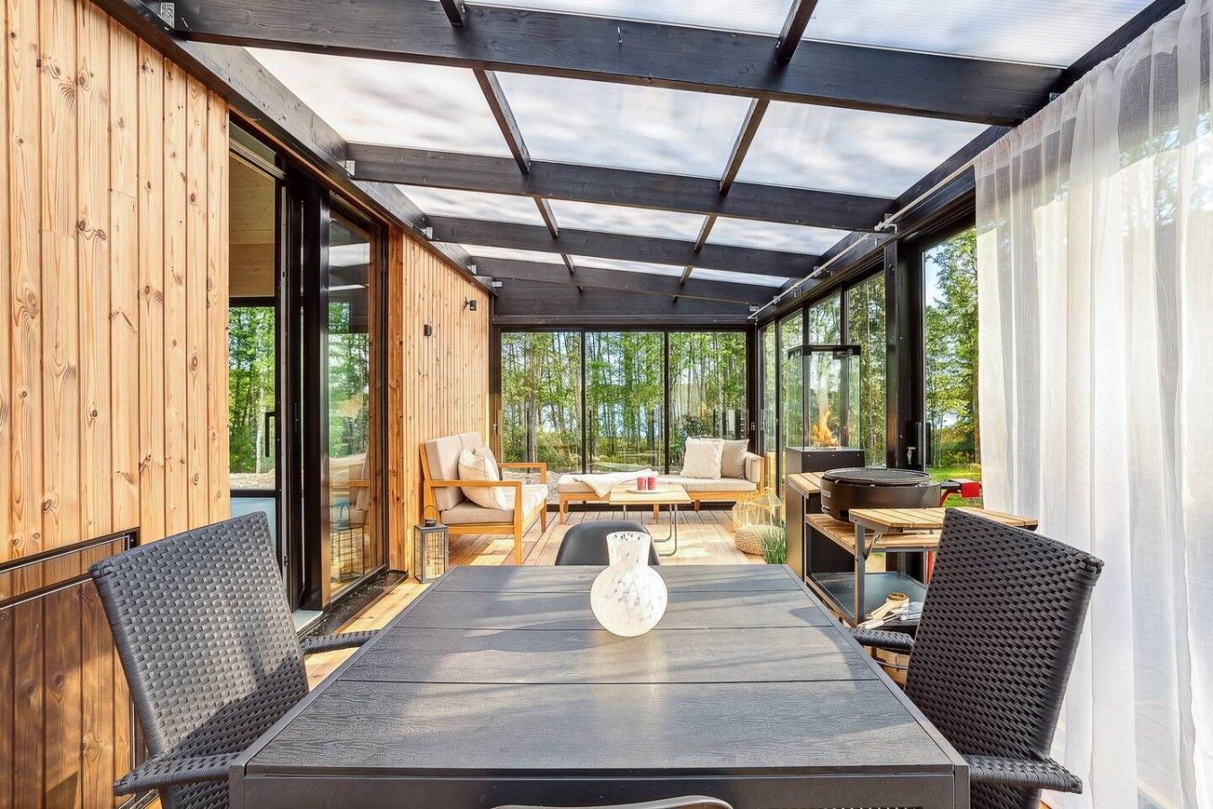 Un espace extérieur aménagé, abrité et doté d’une table et de chaises, d’un canapé et d’une cheminée.