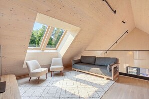A modern loft bedroom with a sloped ceiling, built-in wooden furniture, and a large skylight. - Villa Pickala - Design - Seafront - Hot tub (Siuntio)