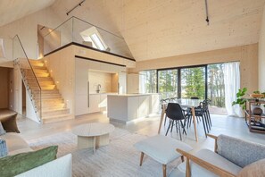 A modern interior with a staircase, a kitchen, dining area, and large windows. - Villa Pickala - Design - Seafront - Hot tub (Siuntio)
