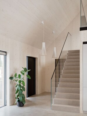 A modern interior with a staircase, wooden walls, and pendant lighting. - Villa Pickala - Design - Seafront - Hot tub (Siuntio)