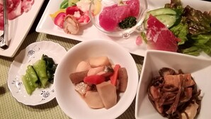 Una mesa con diferentes platos, incluyendo sashimi, verduras y fideos.