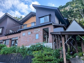A modern building with a brick facade, multiple windows, and a balcony. - pension pure (Iiyama)