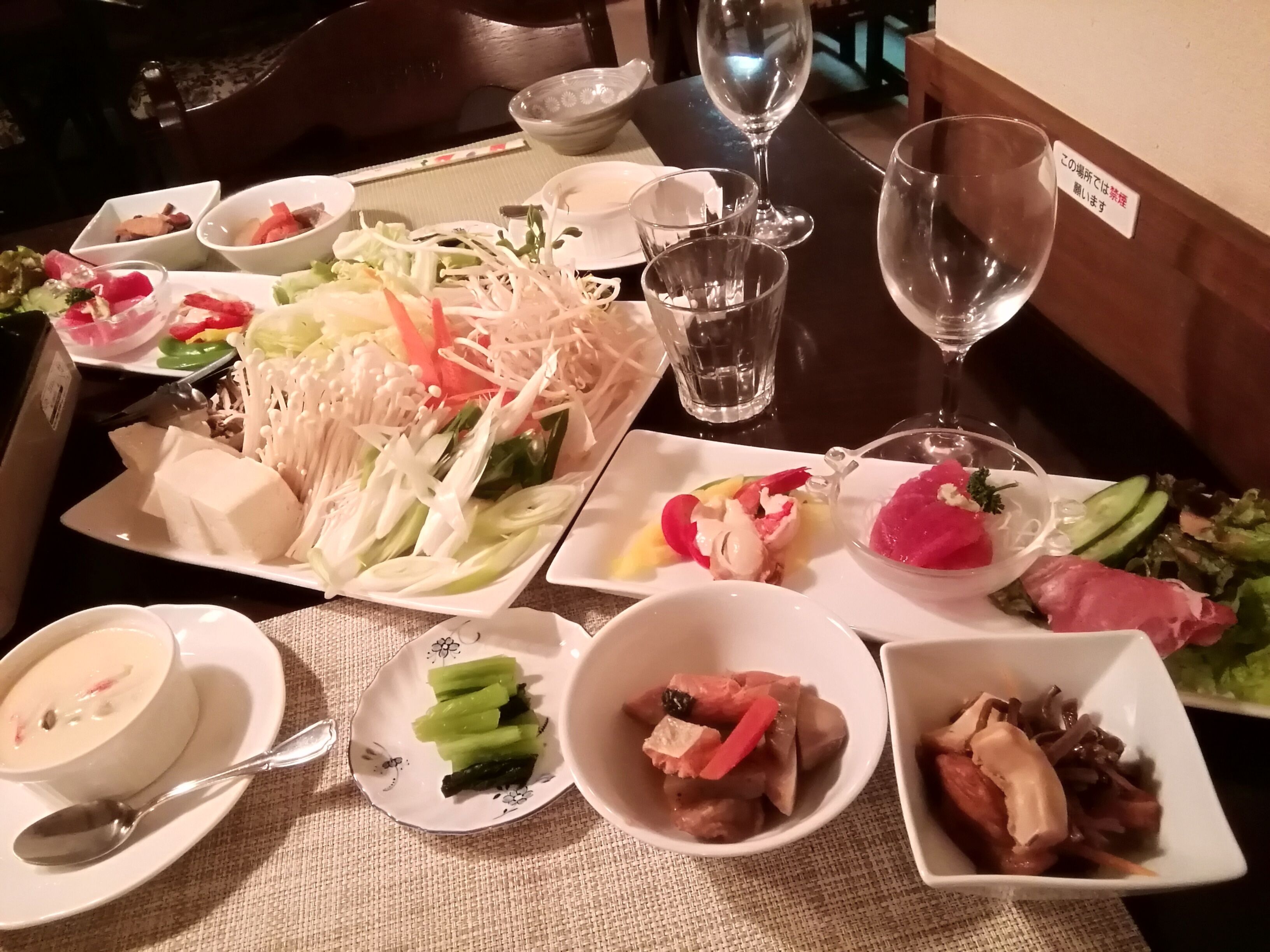 A dining table with various dishes, including vegetables, meat, and a bowl of soup.