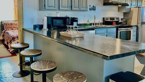 A modern kitchen with grey cabinets, a central island with bar stools, a microwave, a stove, and a refrigerator. - Countryside Inn, Located 9 mi. from the Ark Encounter-Fire pit and Barn games🐮🐮 (Falmouth)
