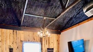 A cozy living room with a leather sofa, a wooden coffee table, a red patterned rug, a television mounted on the wall, and a ceiling with exposed beams. - Countryside Inn, Located 9 mi. from the Ark Encounter-Fire pit and Barn games🐮🐮 (Falmouth)
