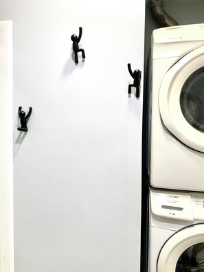 A wall-mounted dryer with a control panel, a vent hose, and three black figurines.