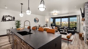 Una cocina moderna con una isla grande, comedor con sofás de cuero y chimenea de piedra.