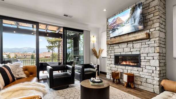 Una sala de estar moderna con sofás de cuero, una chimenea de piedra y un televisor grande montado en una pared de piedra.