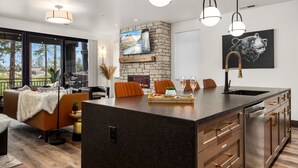 Una cocina moderna con una isla grande, chimenea de piedra y comedor con vistas.