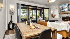 Un comedor moderno con mesa de madera, sillas negras y una chimenea.