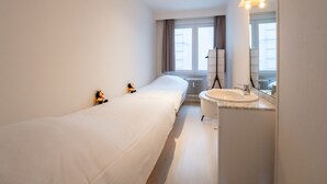 A modern hotel room with a single bed, a bathroom with a sink and mirror, and a window with curtains. - Escape with sea view by Interhome (Blankenberge)