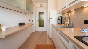 A modern kitchen with white cabinetry, a stainless steel sink, and a coffee machine. - Escape with sea view by Interhome (Blankenberge)