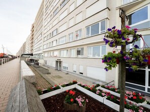 Stylish residential building with balconies and windows, set amidst a beautifully landscaped area.