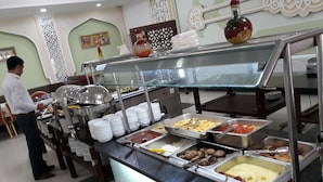 A buffet setup with various food items and a person serving. - Grand Bukhara (Bukhara)