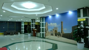 A lobby with a modern ceiling design, a mural of a mosque, and a sign for the lobby bar. - Grand Bukhara (Bukhara)