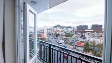 A balcony with a view of a cityscape, including buildings and a busy street.