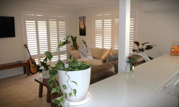 A living room with a sofa, a coffee table, and a potted plant. - Secluded 3 bedroom hideaway, five minutes walk to Main Beach/Town Centre. (Byron Bay)