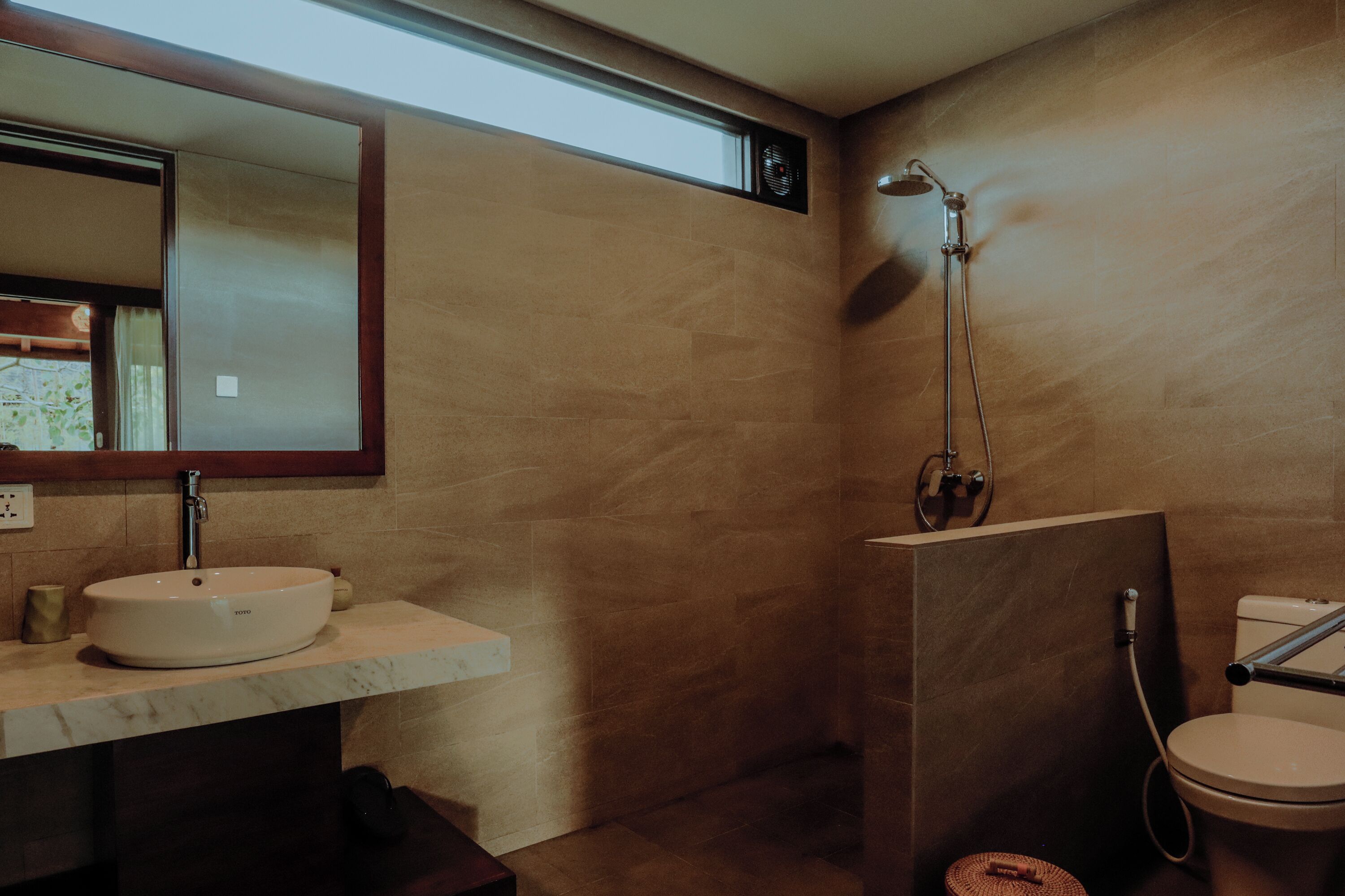 A bathroom with a marble sink, a mirror, a shower, and a toilet.