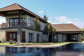 A two-story house with a swimming pool in front.