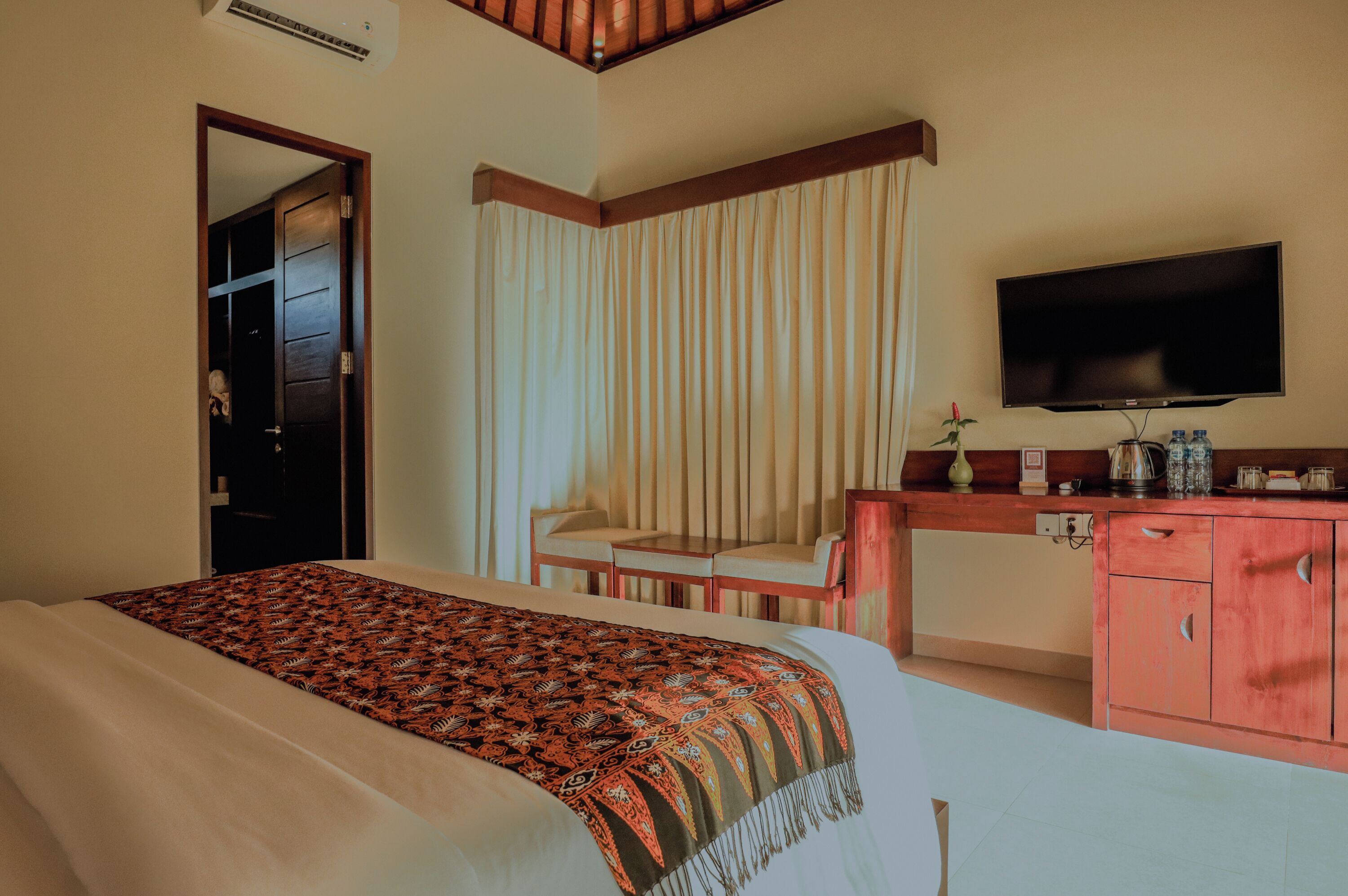 A hotel room with a bed, a desk, a television, and a cabinet.