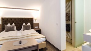 Un dormitorio moderno con cabecera capitonada, una mesita de noche con control remoto y un vestidor con puertas estampadas.