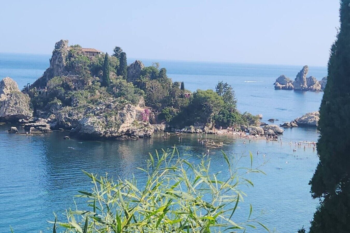 A coastal landscape with rocky terrain and a building on a cliff overlooking the sea.