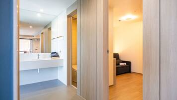 A modern bathroom with a large mirror, a white sink, and a wooden floor.