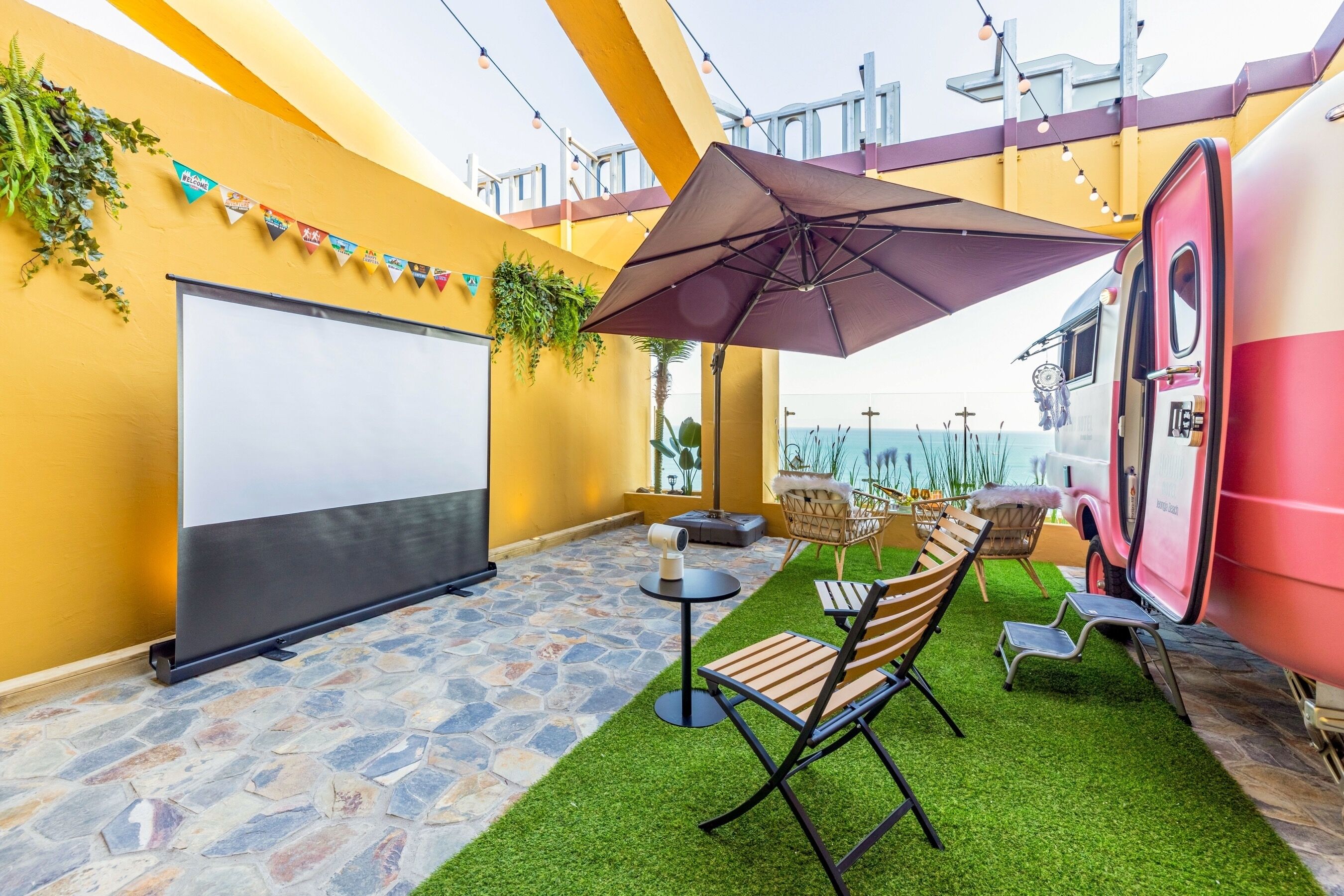 An outdoor seating area with a whiteboard, a table with an umbrella, and chairs.