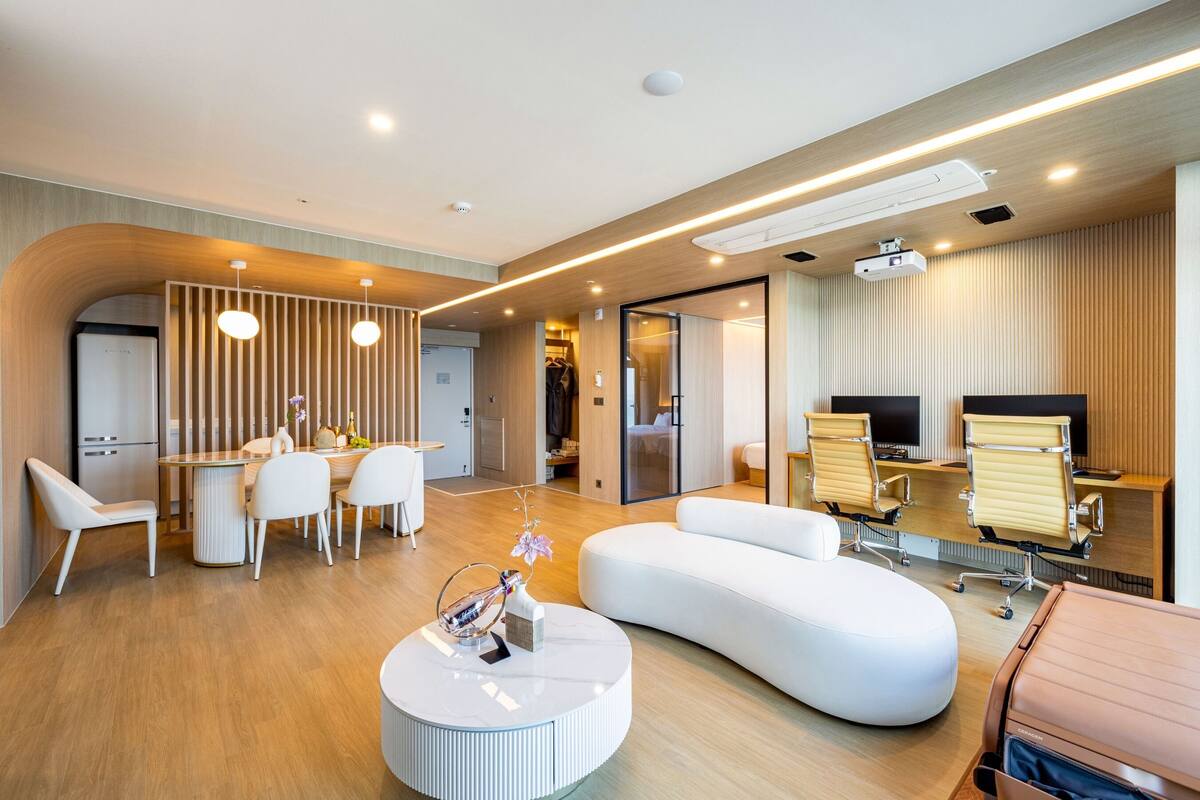 A modern hotel lobby with a dining area, seating, and a large screen.