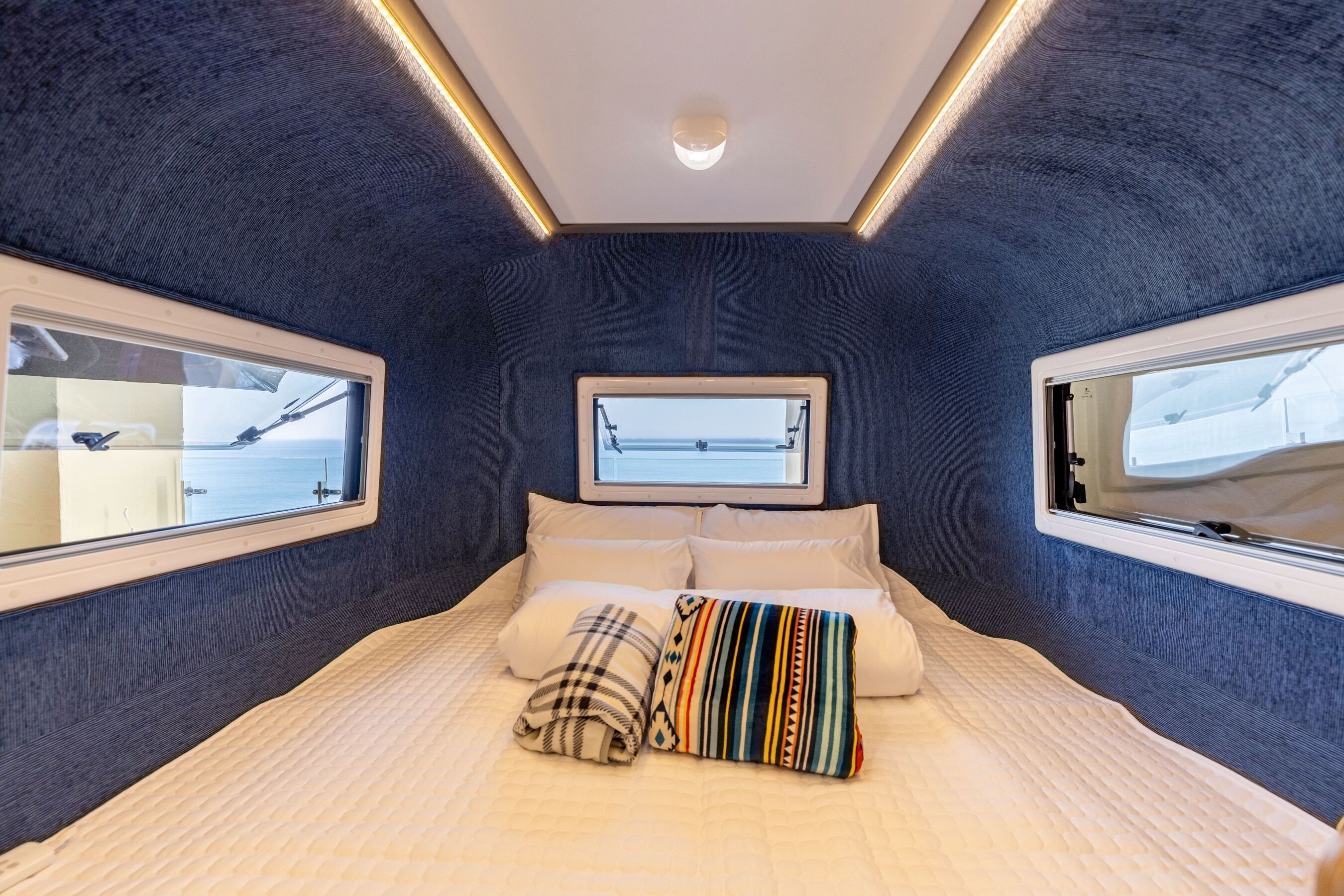 Un dormitorio con una cama grande, dos ventanas y una lámpara en el techo.