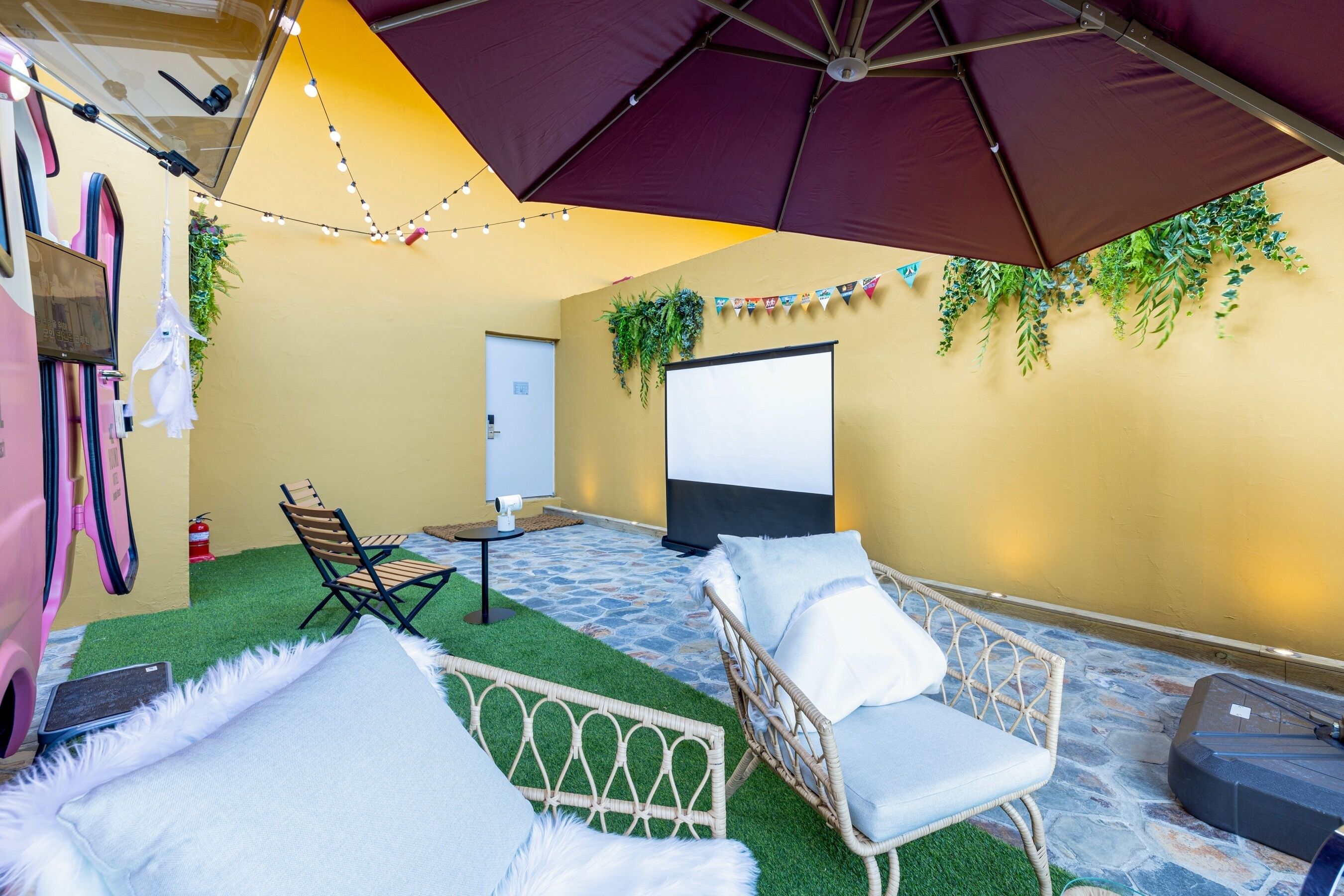 An outdoor seating area with a projector screen, a large umbrella, and a small table.