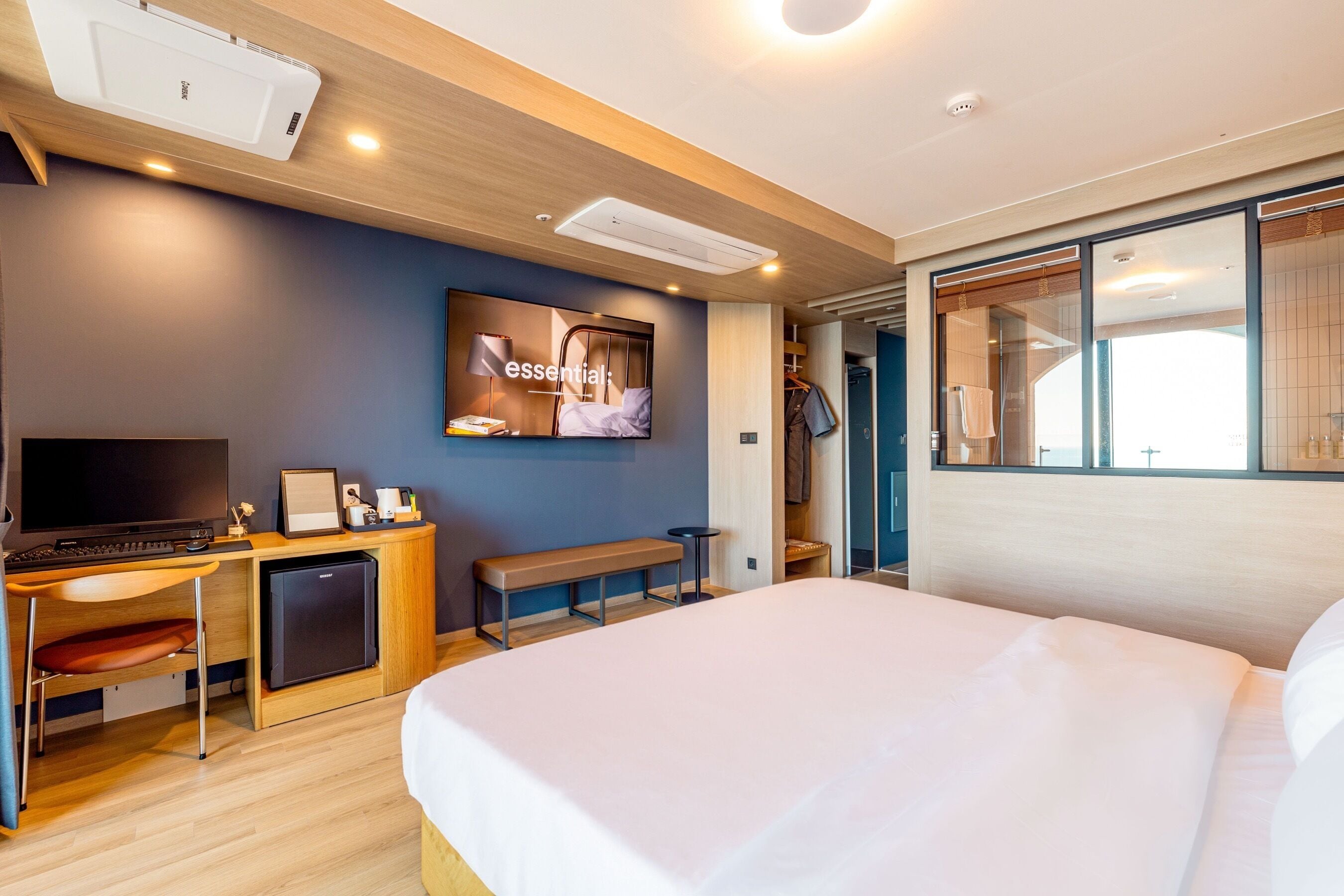 A modern hotel room with a bed, desk, and a television mounted on the wall.