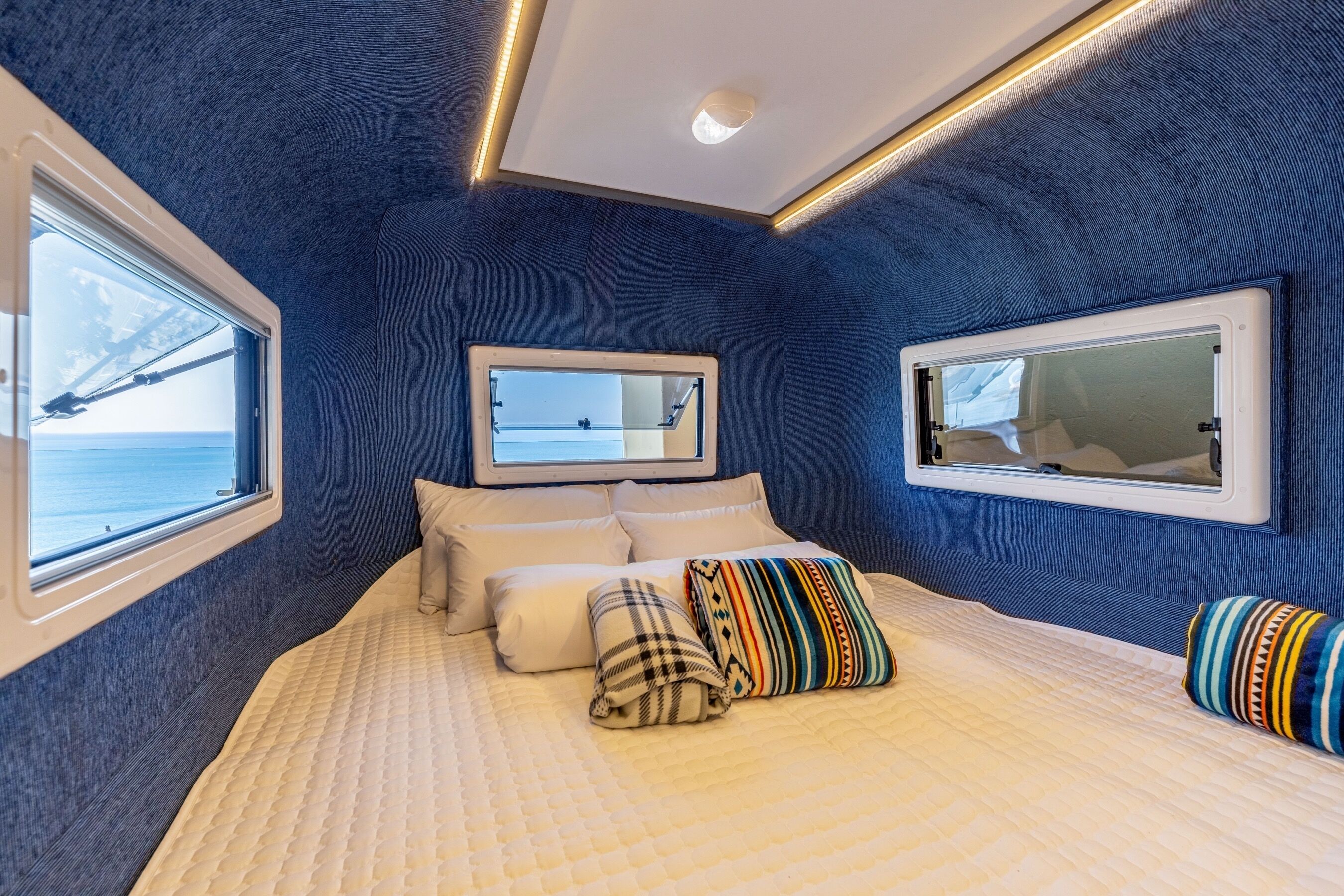 A bedroom with a bed, pillows, a mirror, and a window with a view of a bridge.