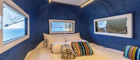A bedroom with a bed, pillows, a mirror, and a window with a view of a bridge.
