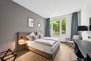 A modern bedroom with a bed, bedside tables, a desk, and a chair. - Home and Coliving Bonn Aparthotel (Bonn)