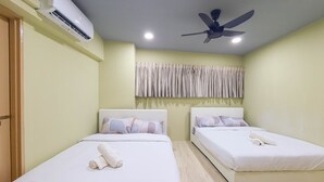 A hotel room with two single beds, an air conditioning unit, a ceiling fan, and a curtain.